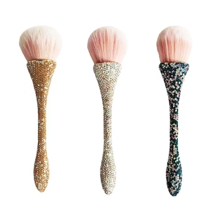 Detailed view of diamond-encrusted makeup brushes with pink gradient bristles in three colors