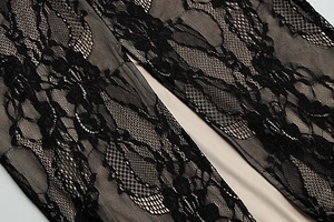 Close-up of black floral lace fabric with beige lining on a square neck evening dress