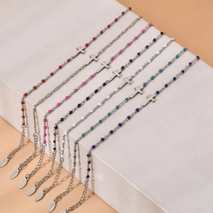 Silver stainless steel cross bracelets with colorful beads on white geometric steps