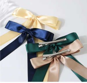 Détail de pinces à cheveux à nœud en satin en quatre couleurs avec clips métalliques