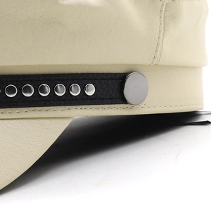 Detailed close-up of cream leather cap showing metal rivets and silver buckle trim