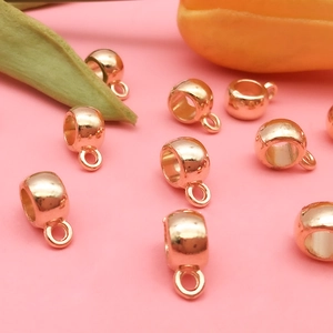 Detailed view of rose gold metal beads with pendant loops for DIY jewelry making
