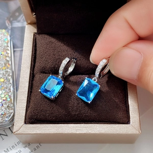 Detail of silver drop earrings with rectangular blue zircon in a brown velvet box