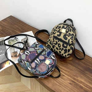 Detailed view of mini printed backpacks with snake and leopard patterns on a wooden bench