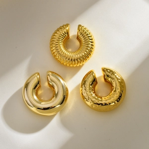 Set of three 18K gold-plated stainless steel textured ear cuffs on white silk fabric