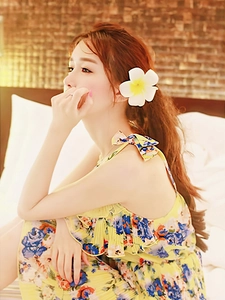 Detail of yellow floral dress with bow straps and frangipani flower hair clip