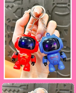 Close-up view of cute red and blue robot astronaut keychains held in hand for bag decor