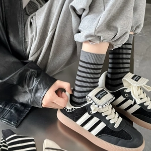 Retro grey and black striped crew socks styled with vintage sneakers for casual street look