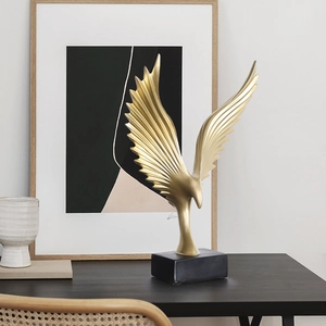 Modern matte gold eagle sculpture with spreading wings on a solid black base for home decor