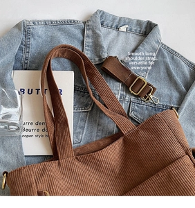 Detail of brown corduroy tote bag showing thick texture and golden metal buckle hardware