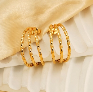 Detailed view of 18k gold triple layered twisted rope hoop earrings on silk background