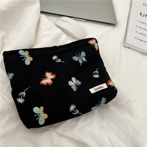 Detail of colorful butterfly embroidery on black canvas cosmetic bag with Sozakka label