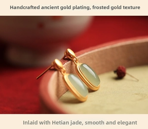 Macro detail of vintage gold-plated Hetian jade earrings with matte floral finish