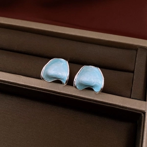 Detailed macro view of light blue enamel C-shape flower earrings in a velvet jewelry box