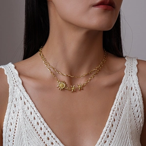 Détail d'un collier double épaisseur doré orné de trois délicats pendentifs tournesol