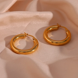 Close-up of gold plated stainless steel hoop earrings on elegant champagne silk fabric