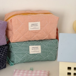 Detailansicht gesteppter Make-up-Taschen im Karomuster mit gewebten Reißverschlusslaschen in Farben