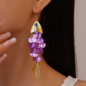 Detail of fish-shaped earrings with purple scales and blue evil eye bead on model