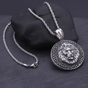Macro detail of vintage lion head pendant on black stone with twisted rope chain
