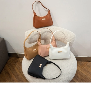 Five assorted colors of leather underarm bags with gold hardware on a white sofa