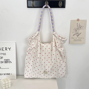 Détail d'un sac cabas en toile blanche avec motif coeur rouge et anse tressée lavande