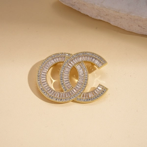 Close-up of interlocking gold brooch with geometric crystals and vintage pearl details