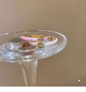 Detail of pink and white enamel rings with rectangular zircons on a glass base