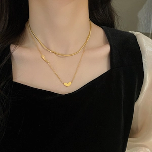 Dettaglio della collana a doppio strato dorata con catena a serpente e pendente cuore