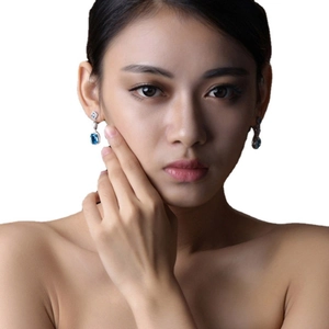 Elegant silver earrings with rectangular blue gemstones and sparkling diamonds on female model
