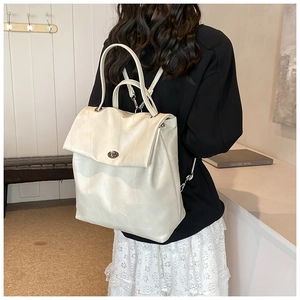 Detail of minimalist cream-white backpack featuring geometric stitching and metal turn-lock