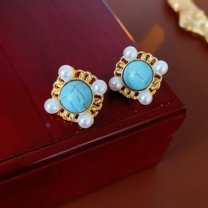 Detailed close-up of vintage gold filigree earrings with turquoise and pearls