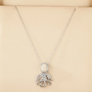 Detail of octopus necklace with white stone head and crystal tentacles on jewelry box