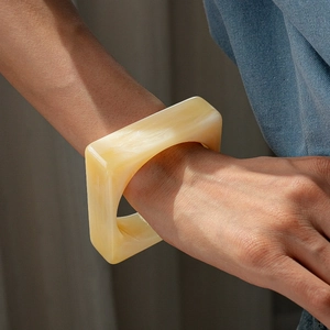 Close-up of a cream marbled acrylic square bangle shown on a wrist for a stylish look