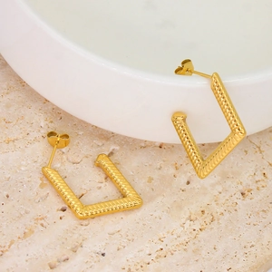 Detailed macro view of gold geometric trapezoid earrings with twisted rope texture