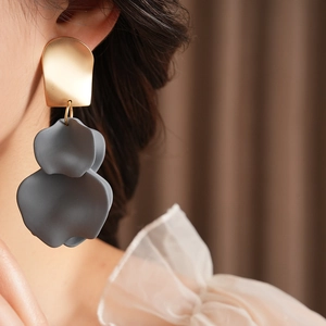Detailed close-up of a model wearing gold and matte grey irregular flower petal earrings