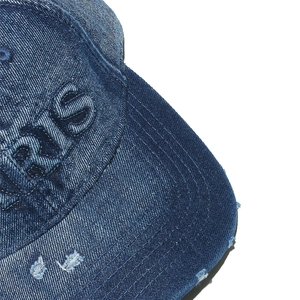 Macro detail of PARIS 3D embroidery and distressed edges on blue denim baseball cap