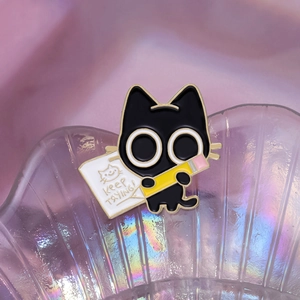 Cute black cat enamel pin holding a pencil with Keep Trying text in shell dish
