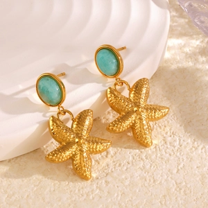 Starfish gold earrings with light blue gemstones on a beach-themed display stand
