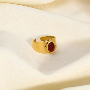 Detailed macro view of an oval red agate gemstone set on a wide gold stainless steel band