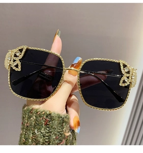 Close-up of golden butterfly rhinestone detail on square metal frame sunglasses
