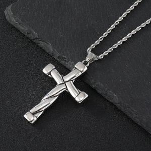 Macro shot of polished silver stainless steel cross pendant on a textured black surface