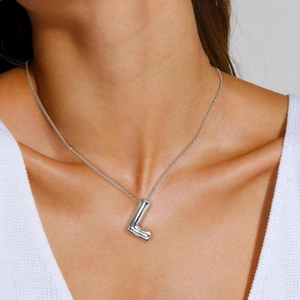Polished silver puffy letter L pendant necklace worn by a model for a chic fashion look