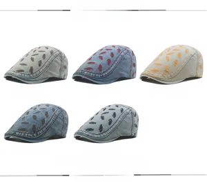 Detail view of washed denim newsboy caps featuring embroidered fishbone patterns in five colors