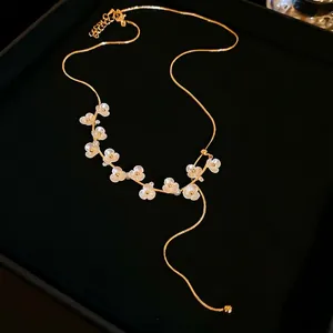 Collana a fiori placcata oro con perle e petali bianchi su fondo di velluto nero