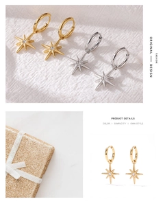 Detail view of gold and silver octagram star drop earrings on beige fabric background