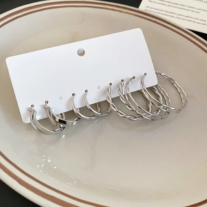 Macro detail of silver twist hoop earrings set on a cream ceramic display plate