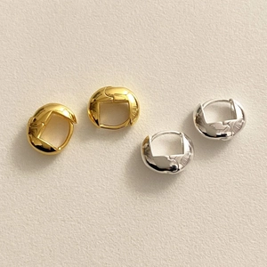 Minimalist oval hoop earrings in polished gold and silver finishes on a textured background