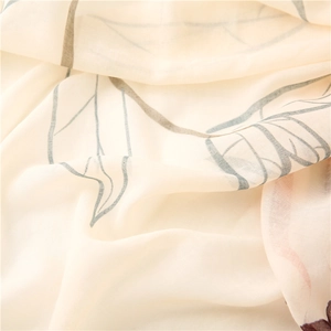 Detailed macro shot of soft cream scarf featuring green leaf print and textile texture