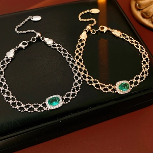 Macro shot of vintage gold and silver bracelets featuring oval green gemstones and diamonds