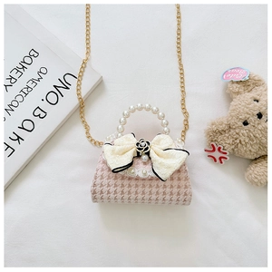 Detailed view of pink houndstooth mini bag with pearl handle and large beige bow